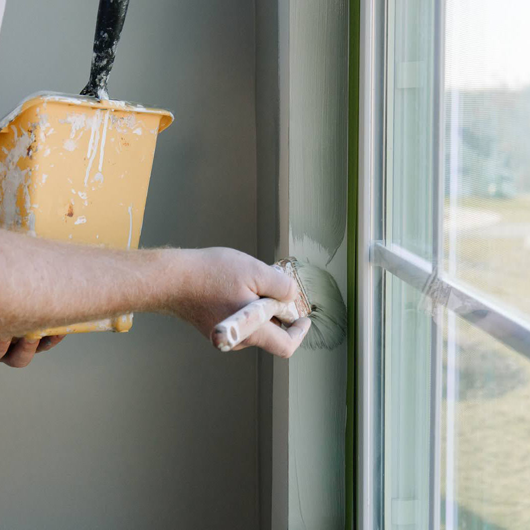 Close up of a painter painting a window sill.