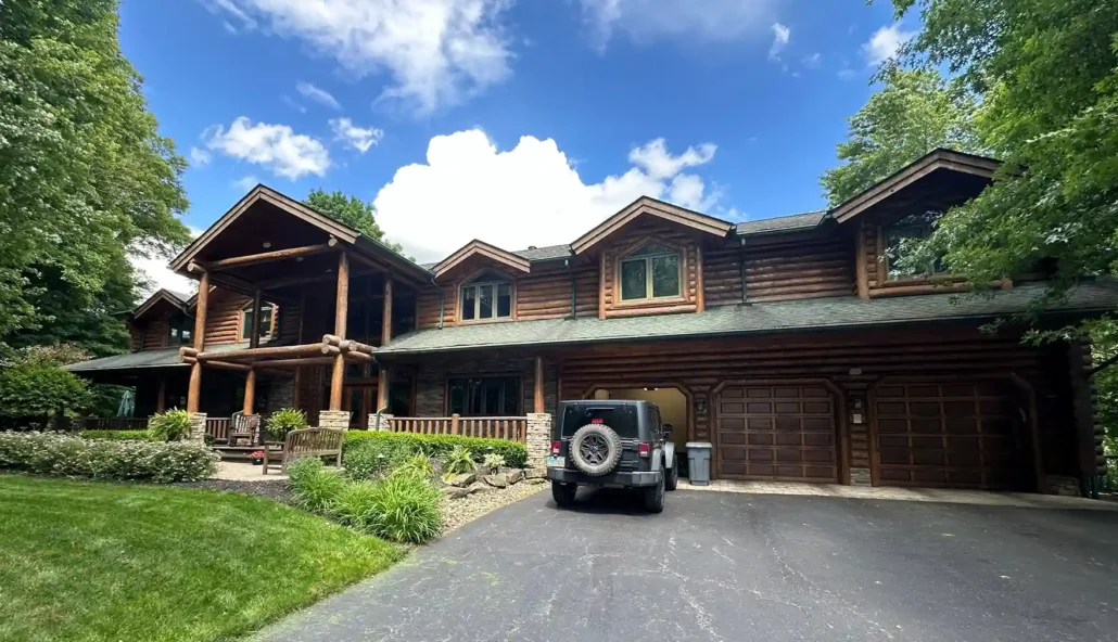 The Front of a Painted and Stained Log Cabin in Boardman Ohio with a Jeep Out Front Shines in the Summer Sun.