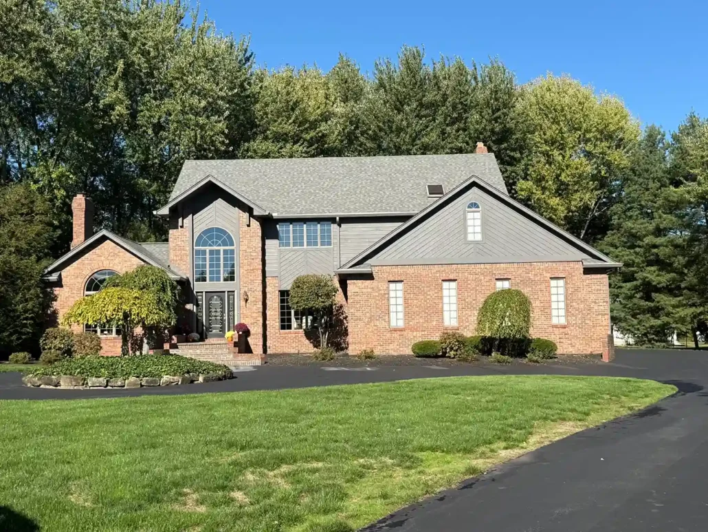 A Brick New Colonial Home with a Black Roof and Black Painted Gables Shines in the Summer.
