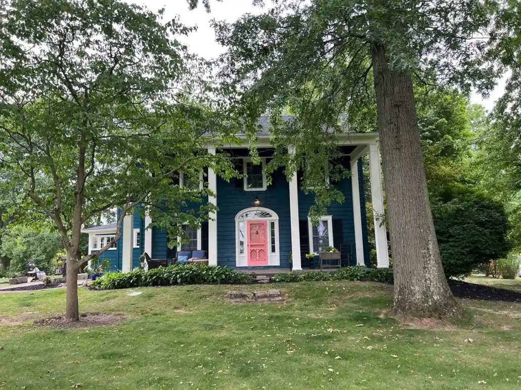 Greek Revival Style Home Exterior in Warren Painted Deep Blue with White Trim and Accents.