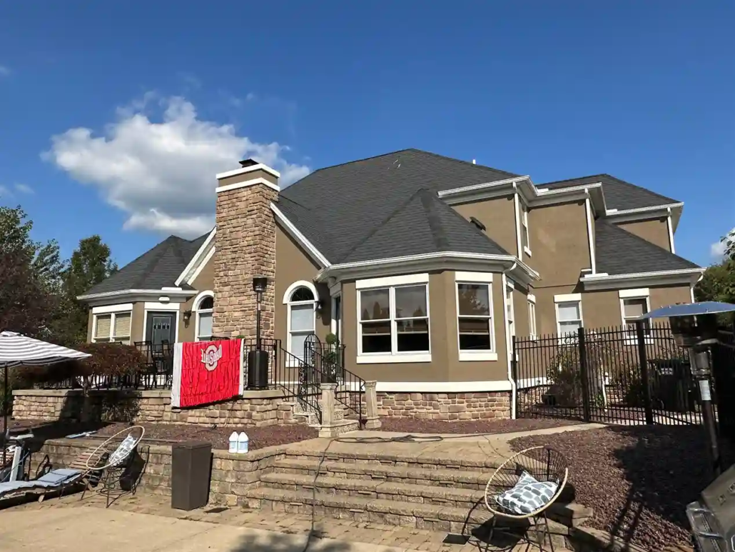 The Backyuard of a Freshly Painted Brown Home with a Stone Base Accent Layer Soaks Up the Sun in New Middletown.