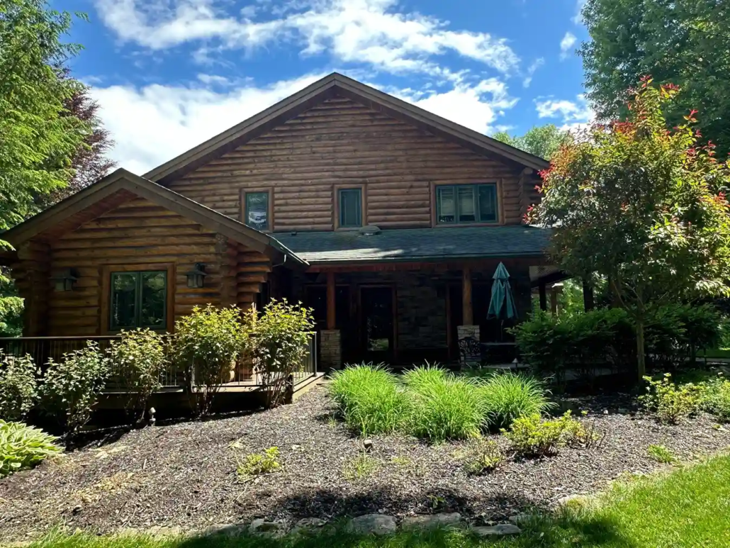 Howland Log Cabin with Green Accents and Roofing Shines in the Howland Sun After Being Stained.