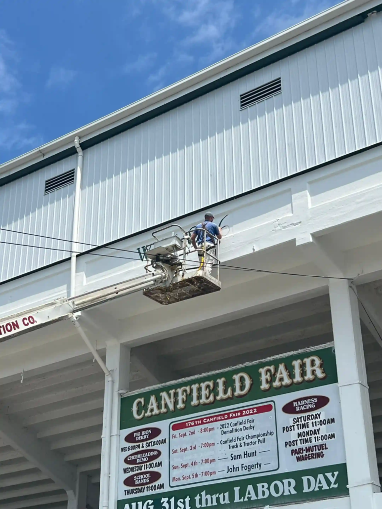 A P&D Painting Employee Paints Numbers on the Freshly Painted White Grandstands Structure at the Canfield Fairgrounds.