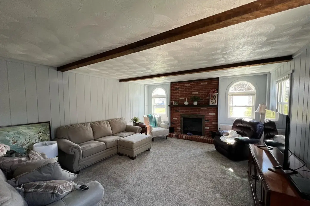 Bright Light Reflects off of White Painted Walls and the Ceiling with Wooden Support Beams Spanning the Width of the Room.